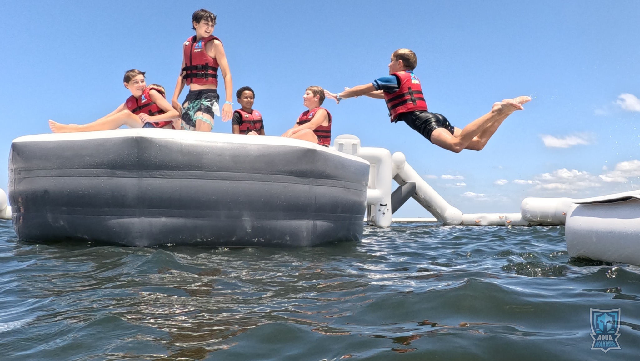 A group of young Aqua Warriors as one participant leaps into the water