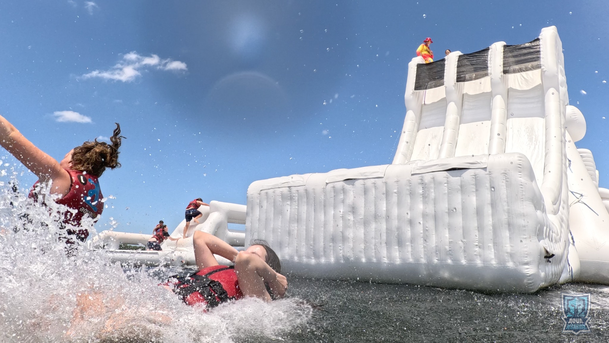 Guests splashing beside the tall Aqua Warrior slide